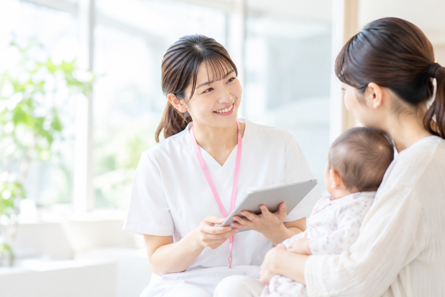タブレットを使いながら親子に相談対応する女性の支援専門職